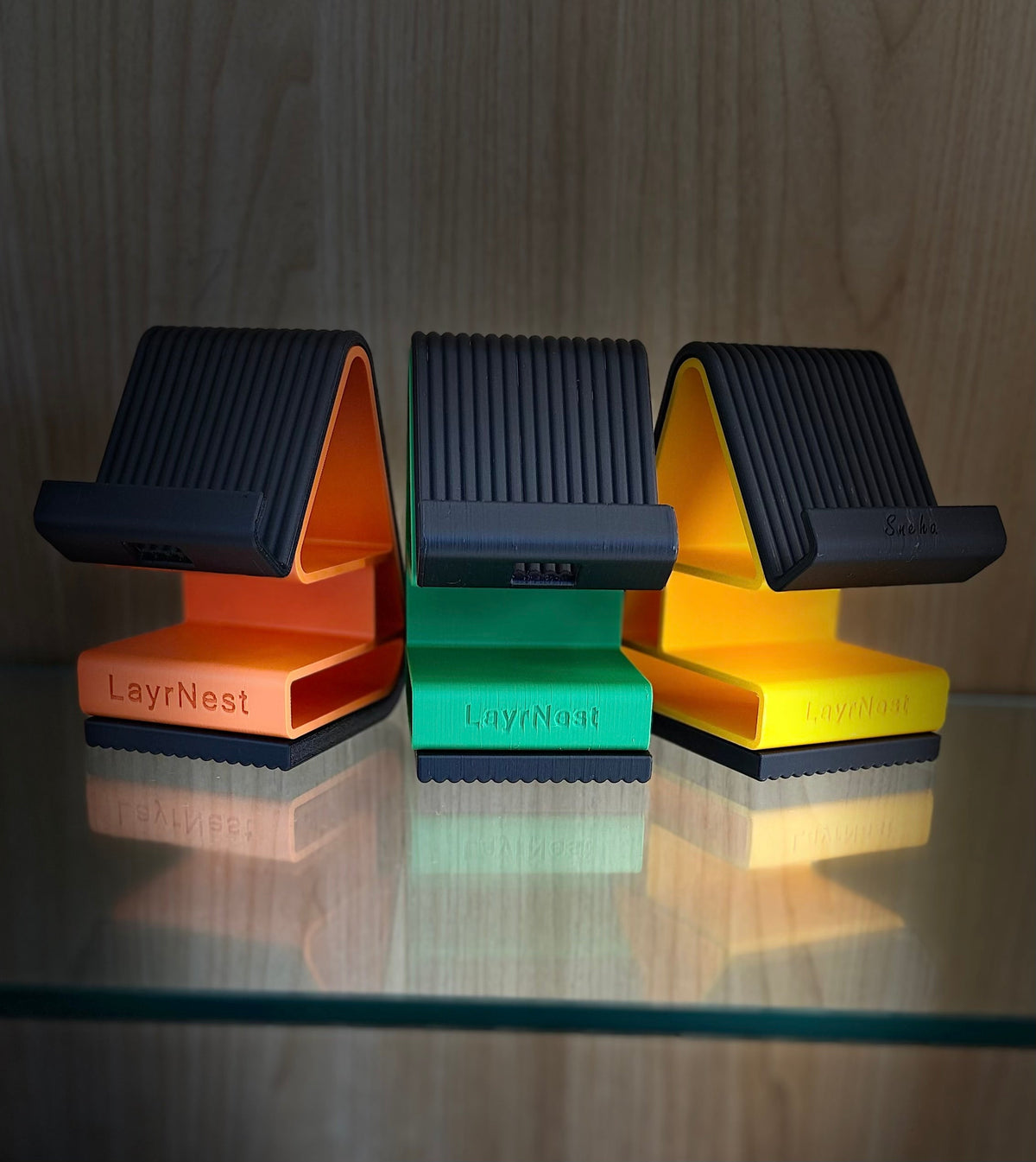 LayrNest Phone Buddy phone stands in orange, teal, and yellow colors