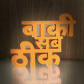 Baaki Sab Theek 3D printed Hindi word art in orange on wooden background